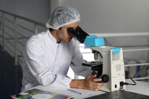 Medical Doctor performs research through a microscope, virology