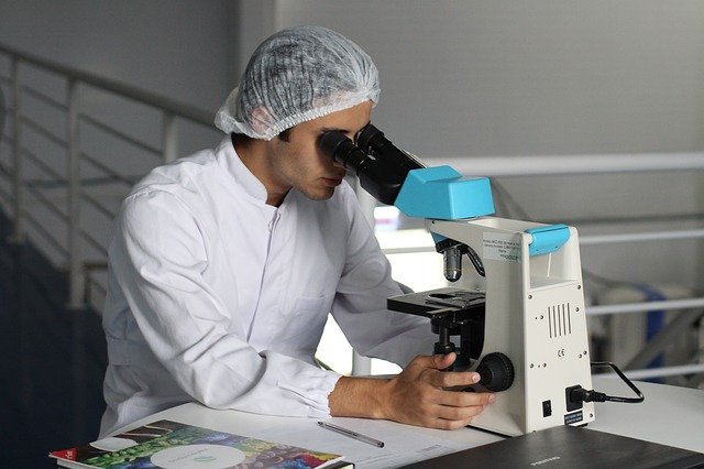 Medical Doctor performs research through a microscope, virology